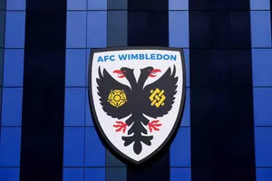 AFC Wimbledon player kicks ball in direction of MK Dons fans in pre-match warmup