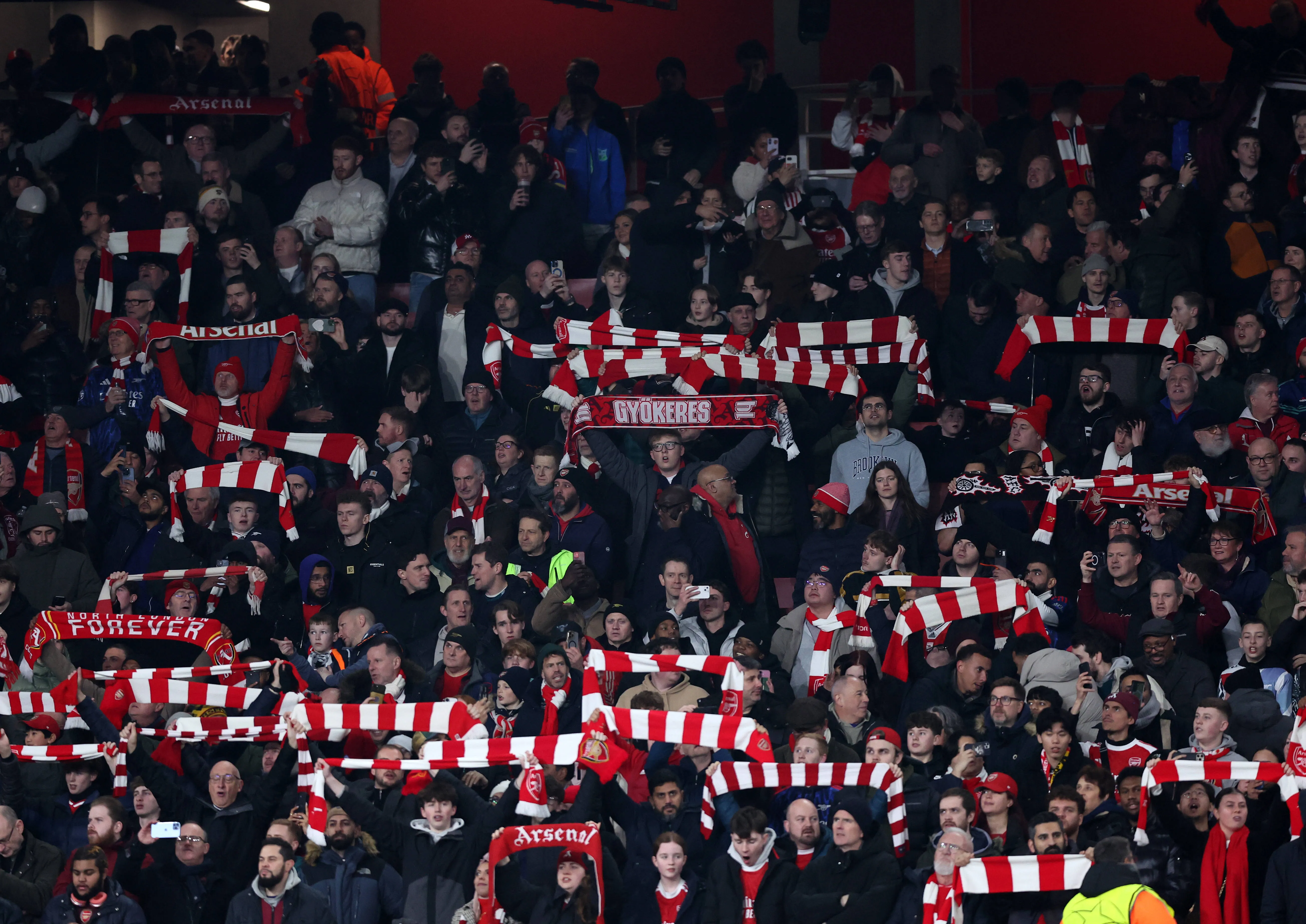 Arsenal fans hold up scarves at Emirates Stadium 